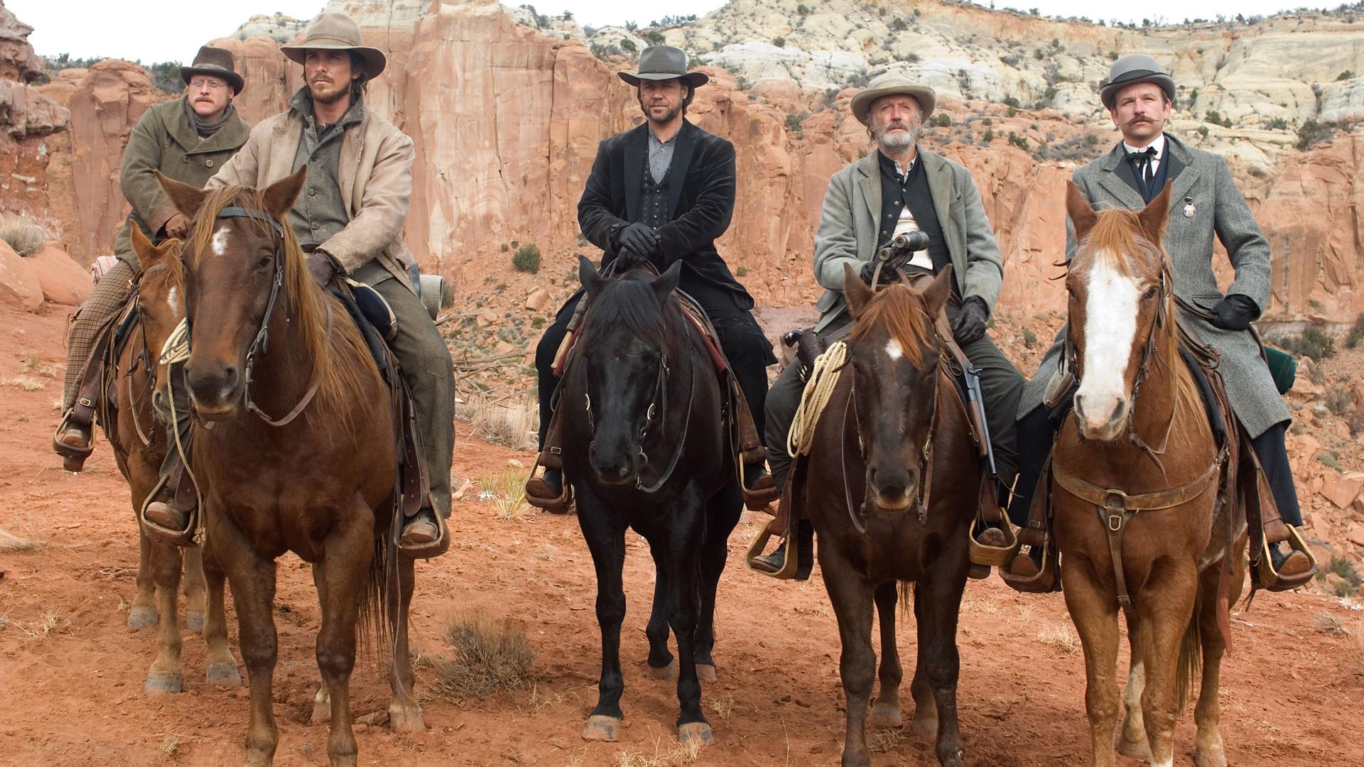 Doc Potter (Alan Tudyk) Dan Evans (Christian Bale), Ben Wade (Russell Crowe), Byron McElroy (Peter Fonda) und Grayson Butterfield (Dallas Roberts) nebeneinander auf ihren Pferden.