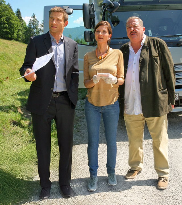"Die Rosenheim-Cops - Tödliche Laster": In den Bergen auf einem Waldweg stehen die Kommissare Hofer (Joseph Hannesschläger) und Hansen (Igor Jeftic) sowie Pathologin Dr. Eckstein (Petra Einhoff) an einem verlassenen LKW.