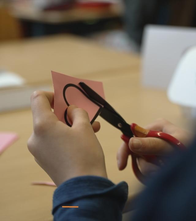Grundschüler schneidet ein Herz aus.