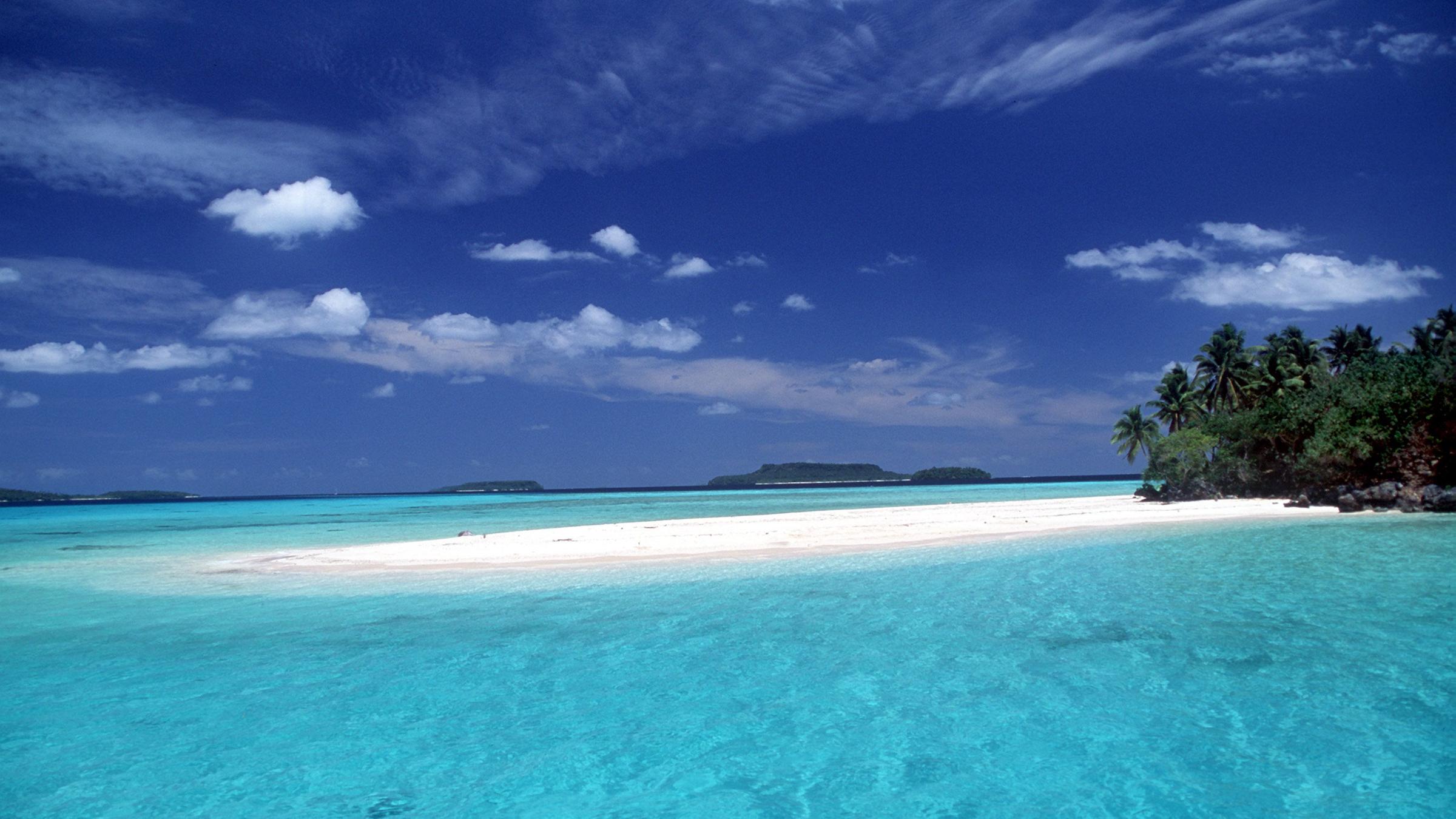 Ein Insel im Pazifik mit weißem Strand und Palmen.