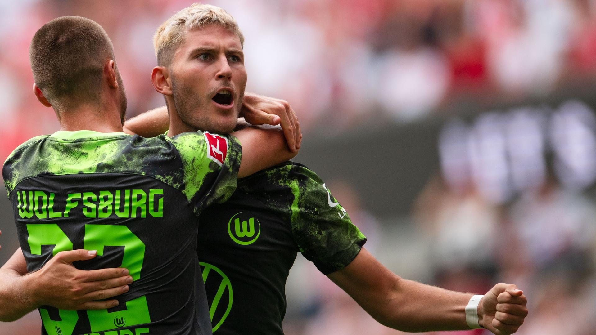 26.08.2023, Nordrhein-Westfalen, Köln: Fußball: Bundesliga, 1. FC Köln - VfL Wolfsburg, 2. Spieltag, RheinEnergieStadion. Wolfsburgs Mattias Svanberg (l) und Torschütze Jonas Wind jubeln nach dem Treffer zum 1:1 Ausgleich.