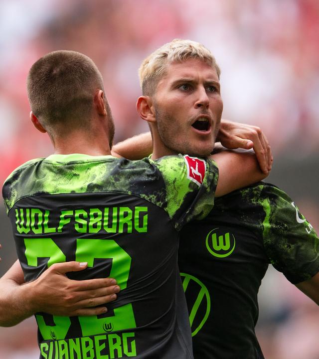 26.08.2023, Nordrhein-Westfalen, Köln: Fußball: Bundesliga, 1. FC Köln - VfL Wolfsburg, 2. Spieltag, RheinEnergieStadion. Wolfsburgs Mattias Svanberg (l) und Torschütze Jonas Wind jubeln nach dem Treffer zum 1:1 Ausgleich.