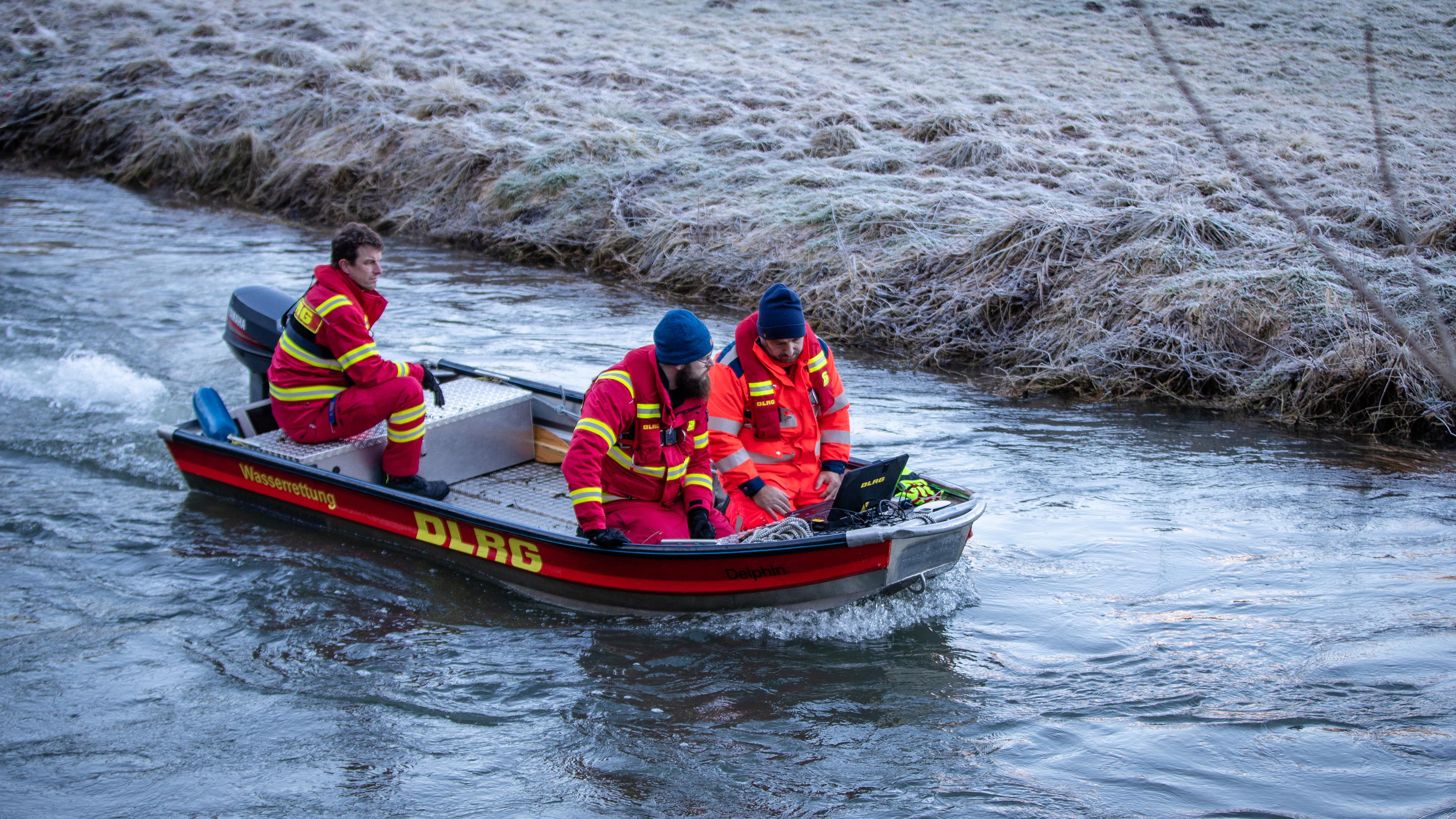 Einsatzkräfte der DLRG, in rot gekleidet, suchen per Sonarabsuche das Gewässer der Lauchert ab.
