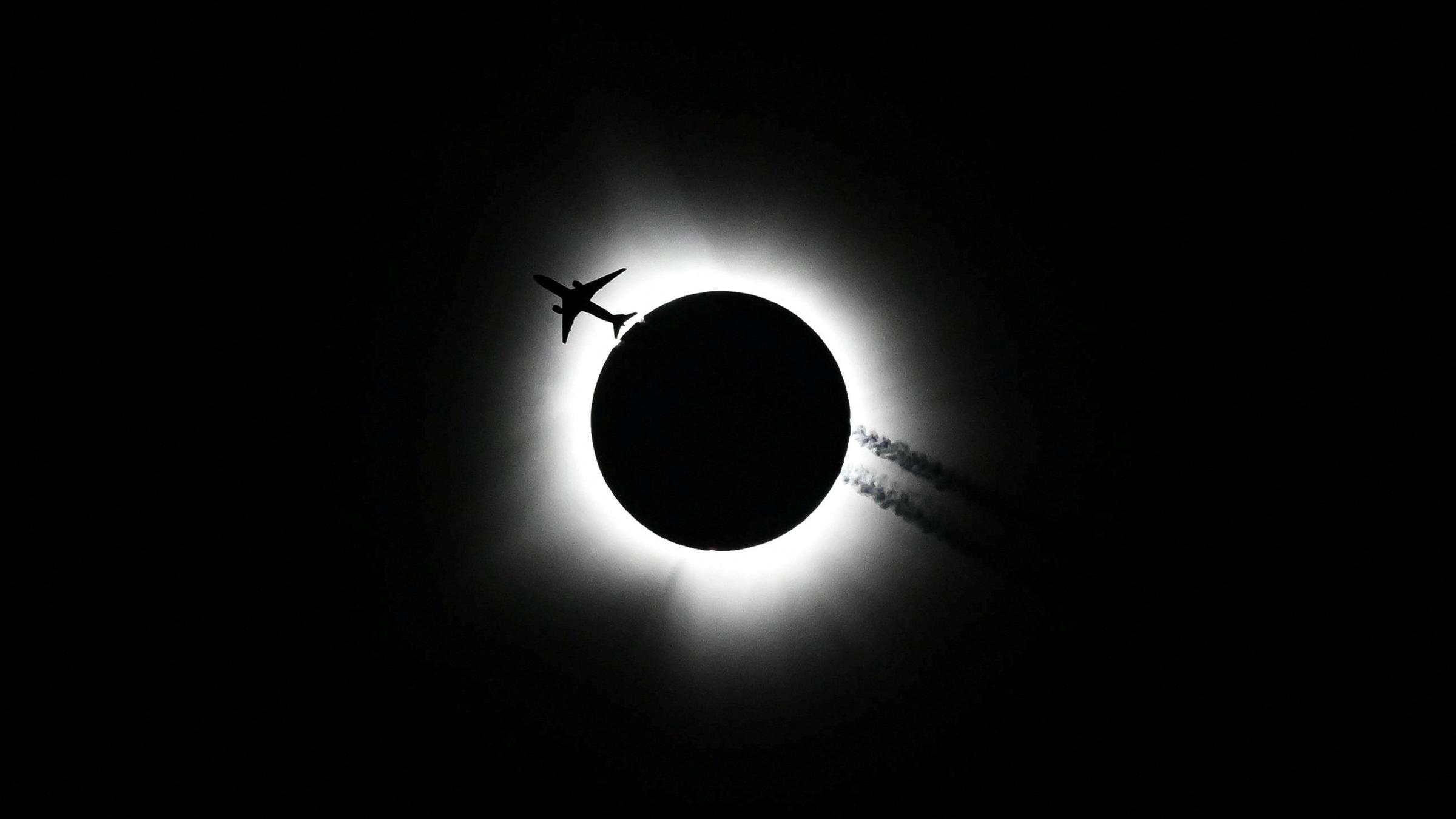 Ein Flugzeug fliegt vor der totalen Sonnenfinsternis im Himmel.