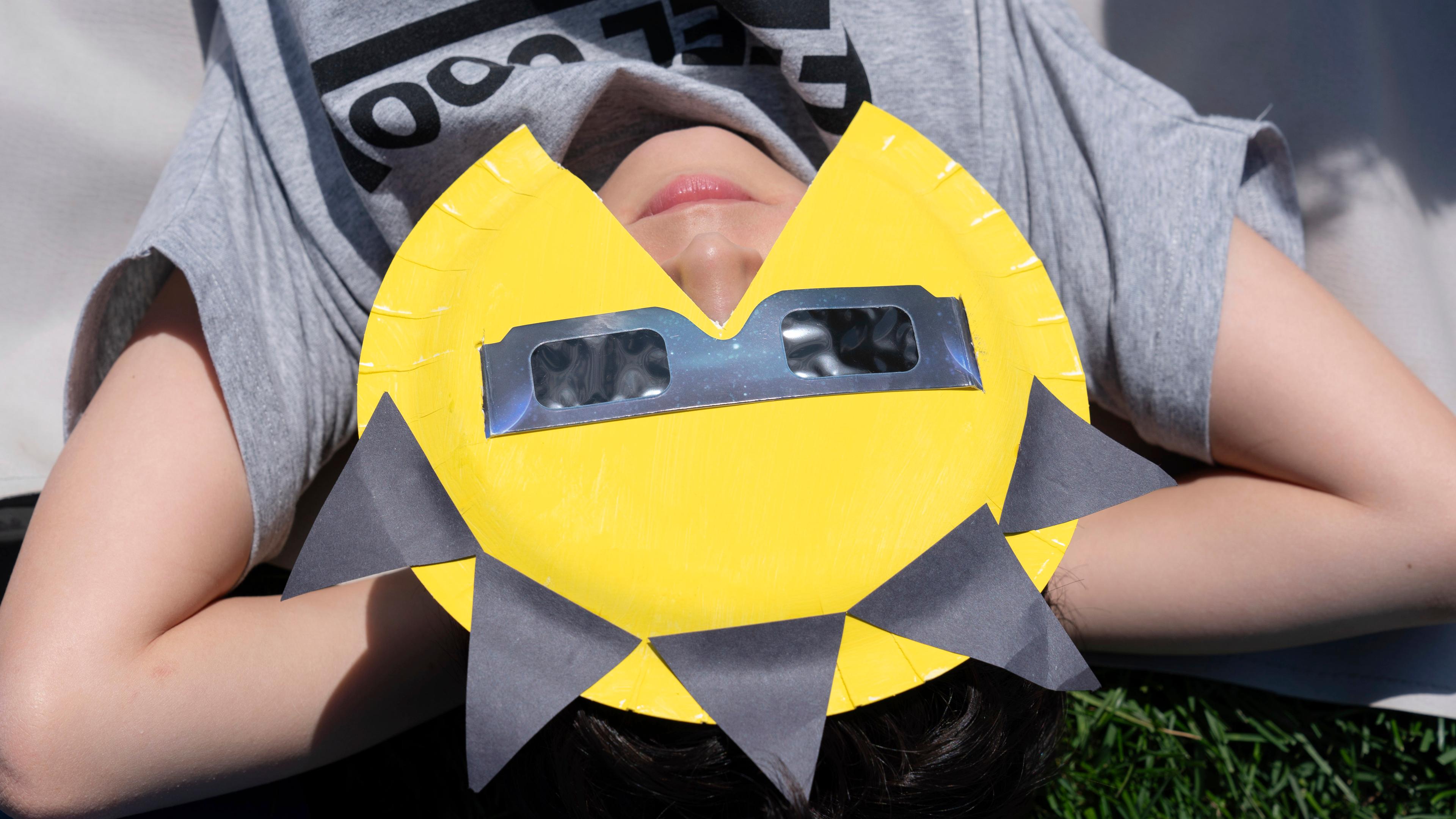 Eine Person trägt eine Schutzbrille, um die totale Sonnenfinsternis zu beobachten.