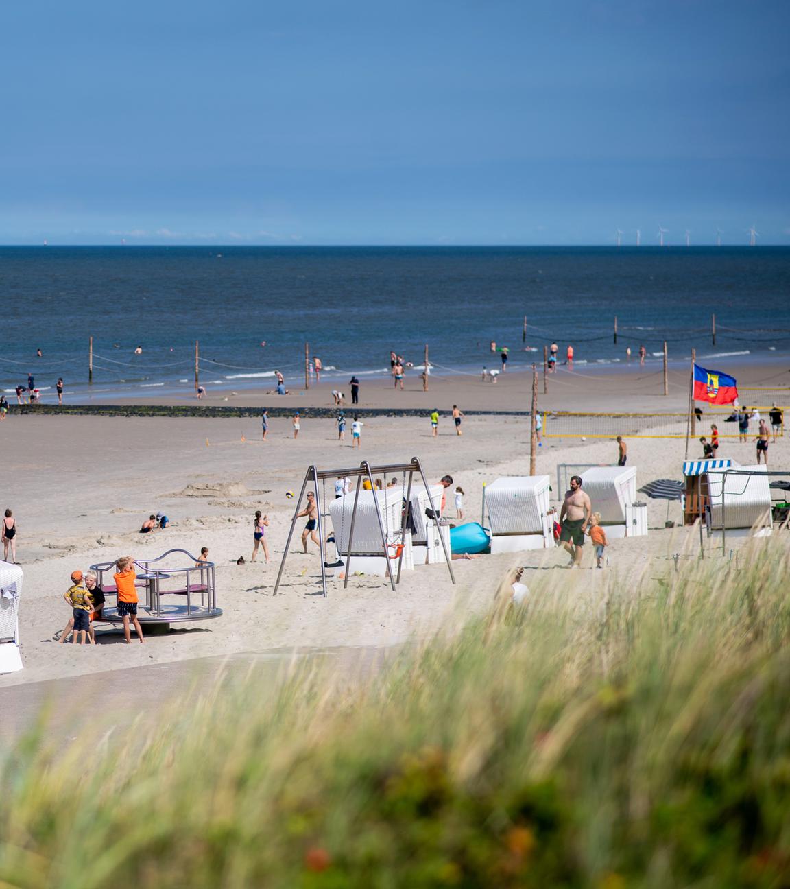Zahlreiche Touristen sitzen bei sonnigem Wetter in Strandkörben am Strand der Insel Wangerooge