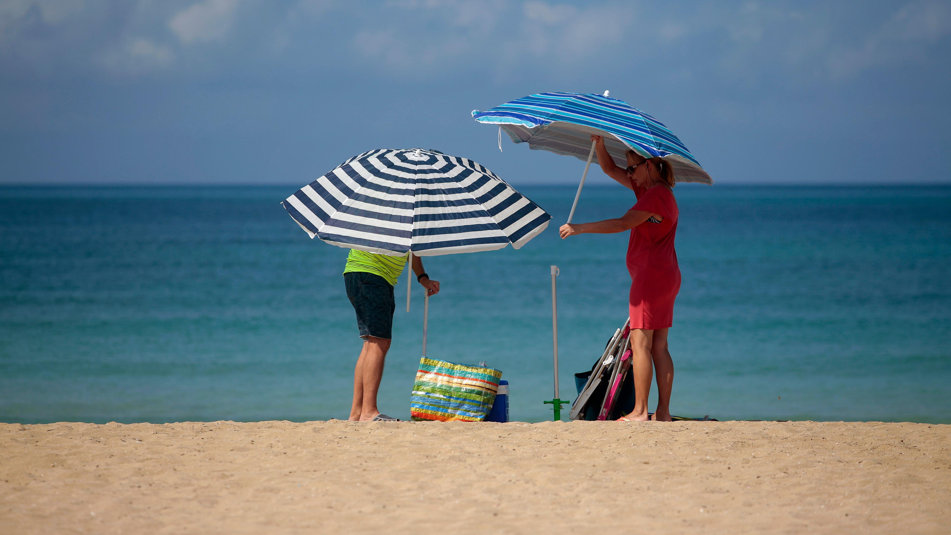Spanien, Palma de Mallorca: Ein Paar stellt Sonnenschirme am Strand von Palma de Mallorca auf.