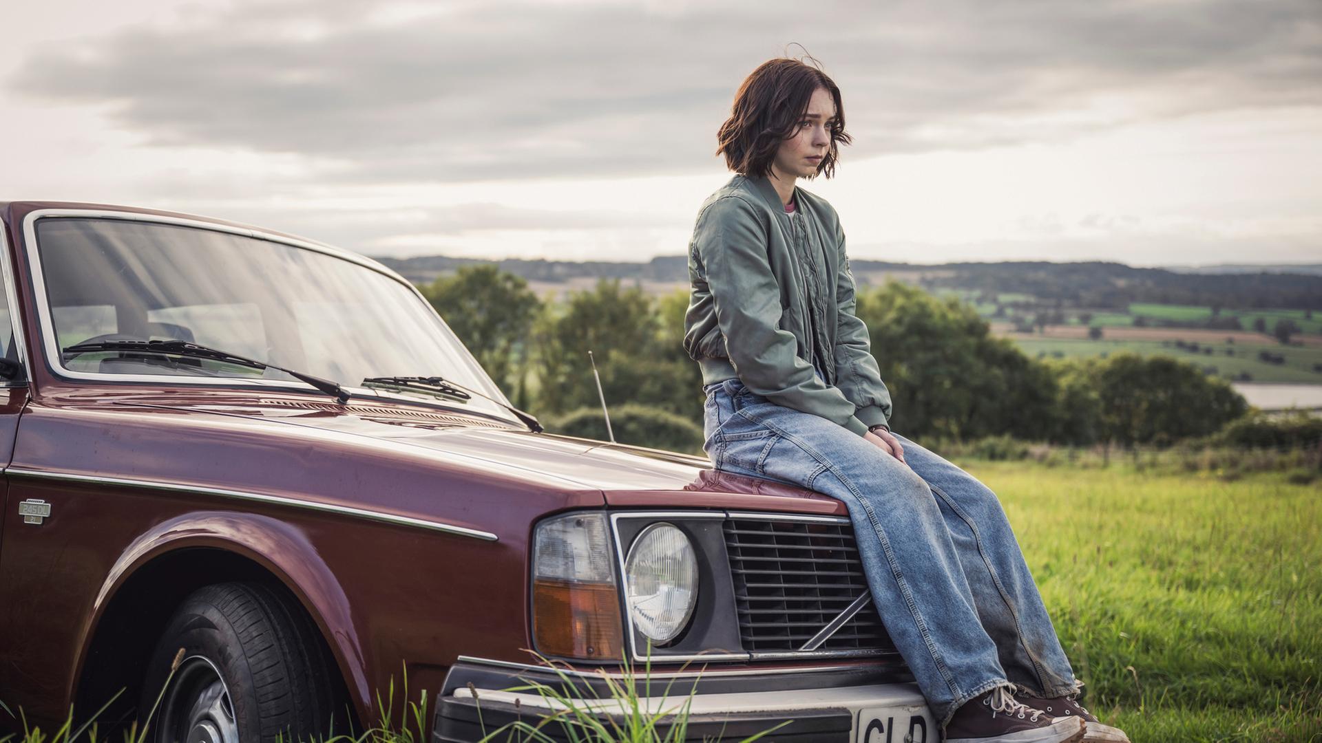 Pip (Emma Myers) sitzt auf einem roten Auto