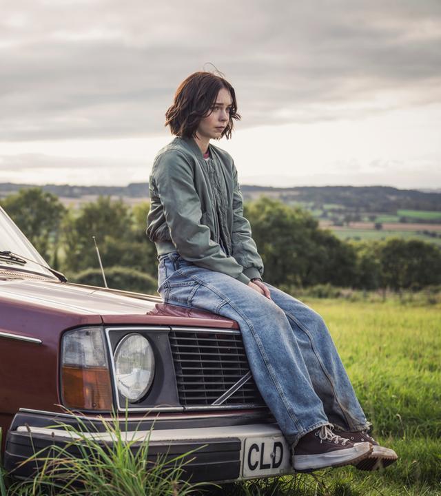 Pip (Emma Myers) sitzt auf einem roten Auto