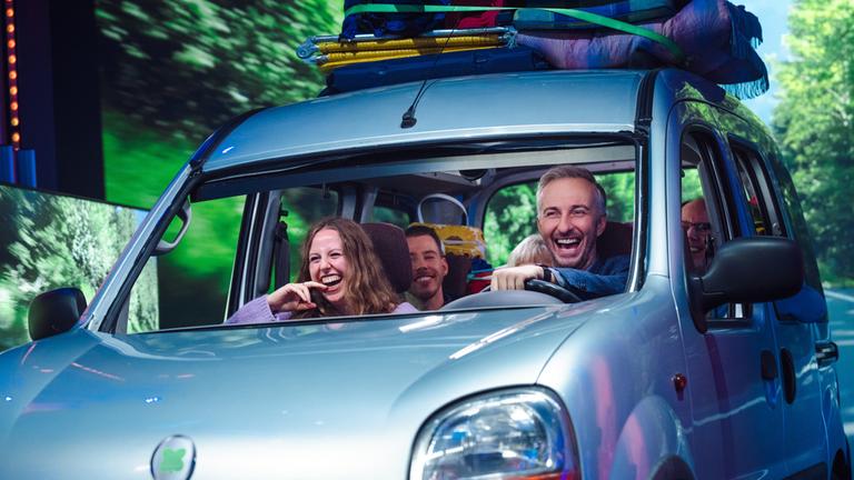 Jan Böhmermann sitzt in einem Auto neben derKandidatin Inez, beide lachen.