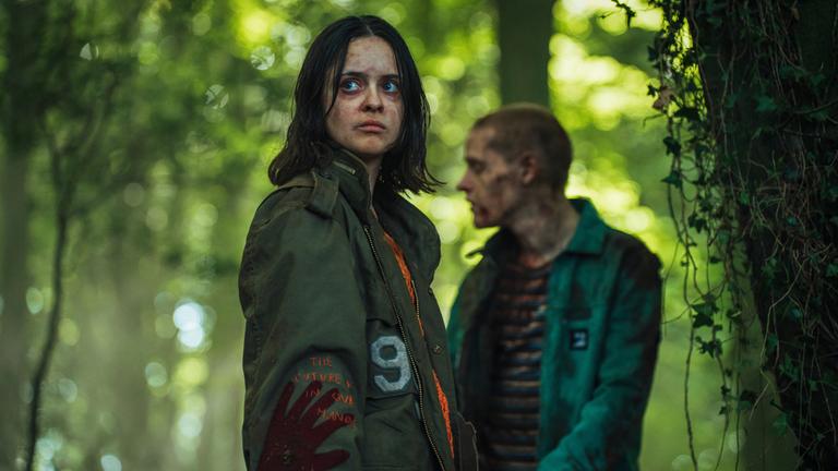 "Generation Z": Finn (Viola Prettejohn) steht in einem Wald. Hinter ihr steht Steff (Lewis Gribben) mit Blutspuren im Gesicht.