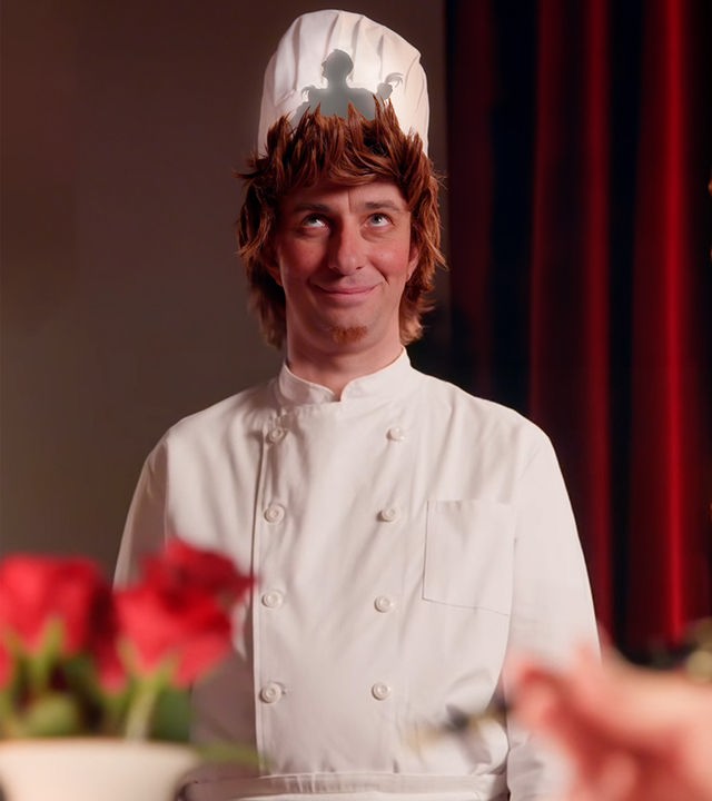 Jan Böhmermann trägt eine weiße Kochmütze, hinter der ein Schatten zu erkennen ist. Die Inszenierung nimmt Bezug auf den Animationsfilm "Ratatouille".