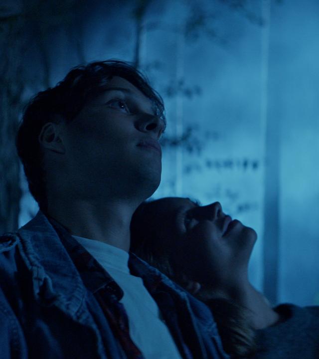 Ein junges Paar im dunklen Wald.