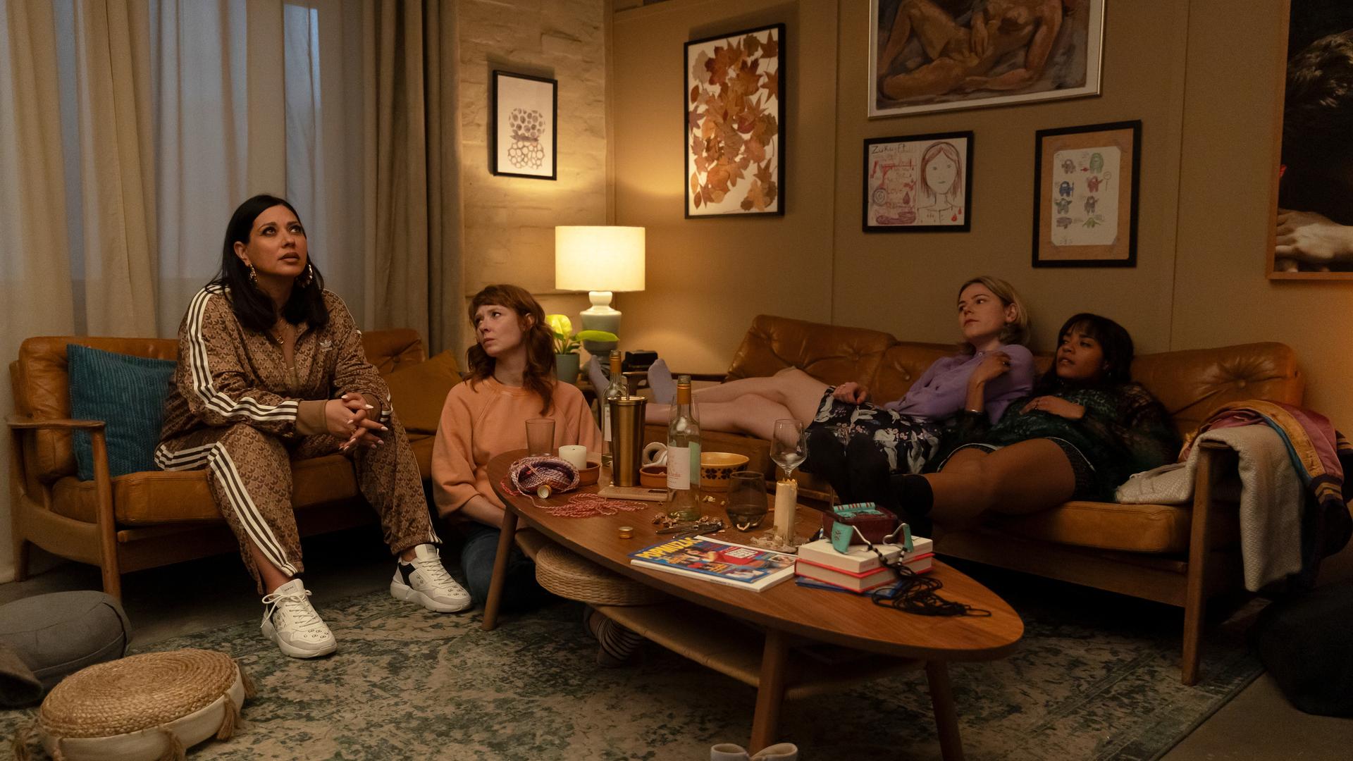 Elif (Jasmin Shakeri), Lena (Sarah Bauerett), Franzi (Llewellyn Reichman) und Jo (Salka Weber) sitzen um einen Wohnzimmertisch herum.