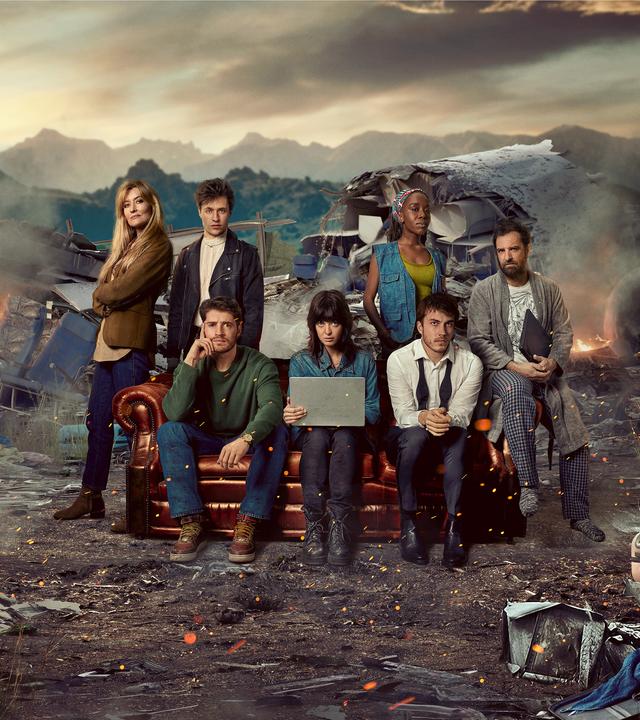 Das Rechercheteam "The Kollective" sitzt auf einer Couch zwischen Trümmern eines abgestürzten Flugzeugs.