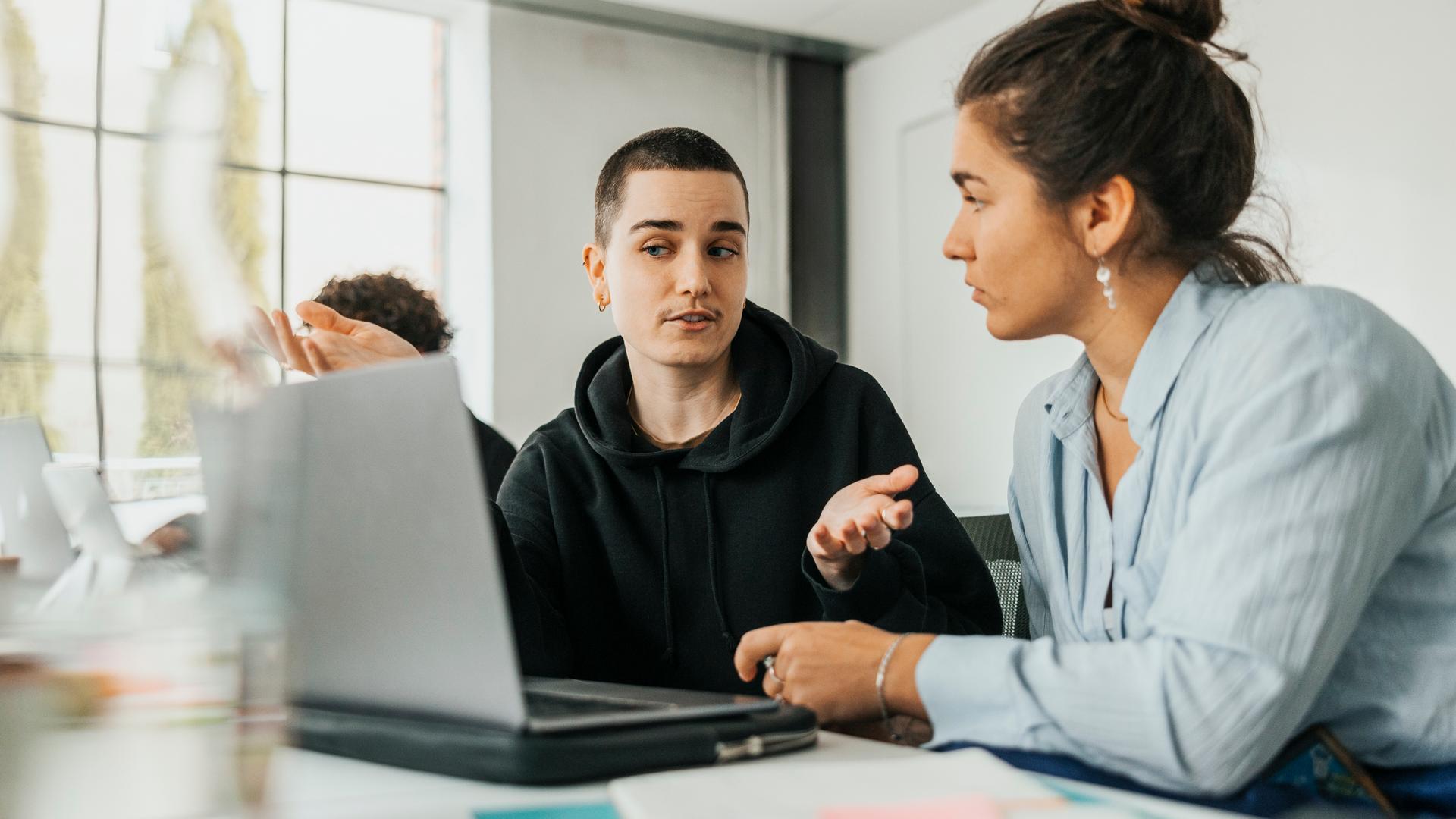 Typical für ZDF Trainee Schwerpunkt Medienrecherche: Zwei Junge Menschen besrepchen sich vor einem Laptop am Schreibtisch sitzend
