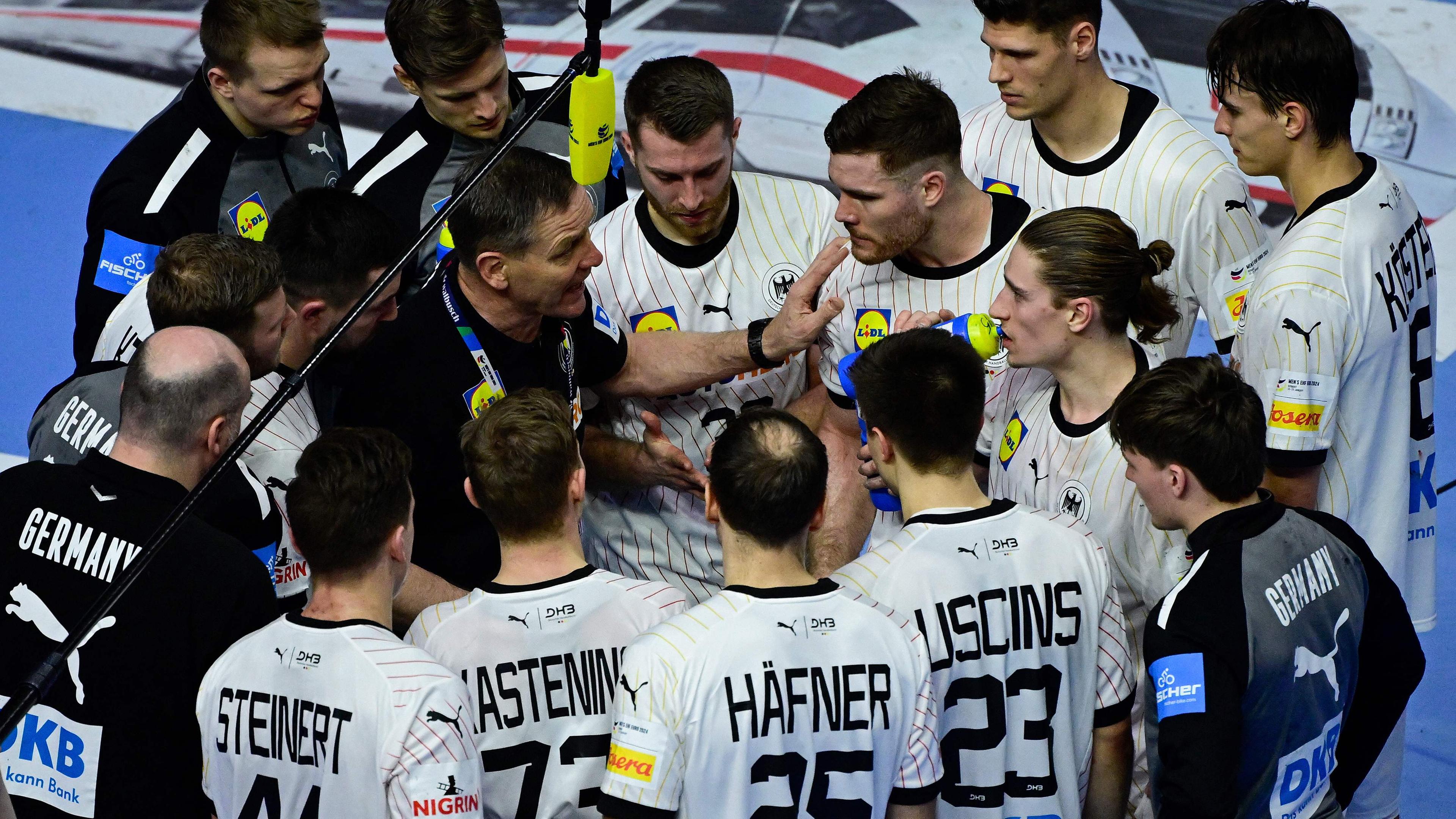 Es ist das deutsche Handball-Team zu sehen. Sie stehen in einem Kreis um den Trainer Alfred Gislason herum.