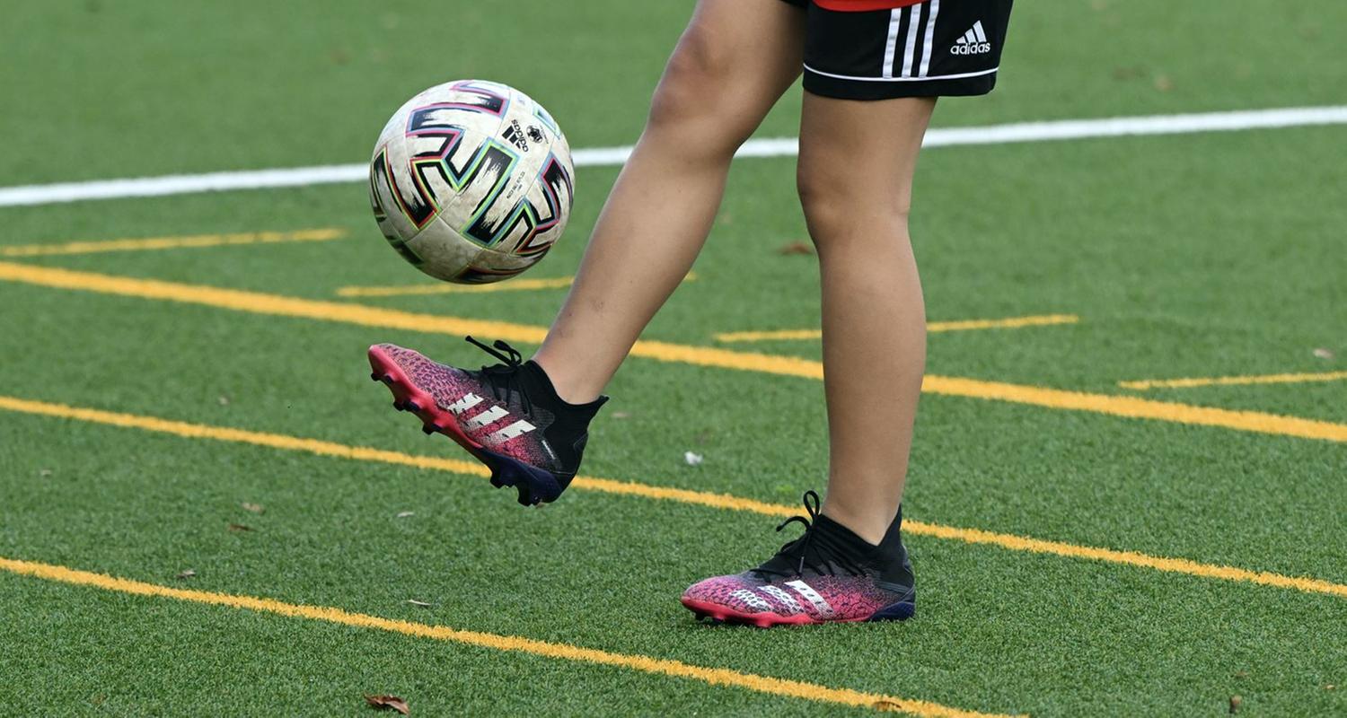 Fußballplatz mit Spielerinn die Ball kickt