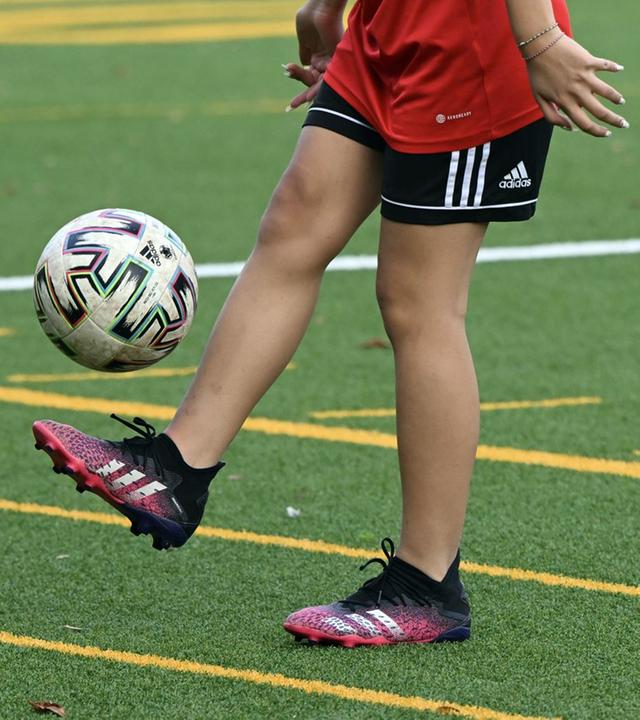 Fußballplatz mit Spielerinn die Ball kickt