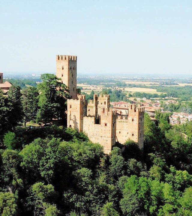 Die mittelalterliche Burg Rocca Viscontea liegt auf einem bewaldeten Hügel.