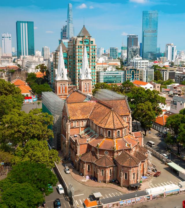 Aufnahme der Notre-Dame Kirche in Saigon vor der Skyline der Stadt
