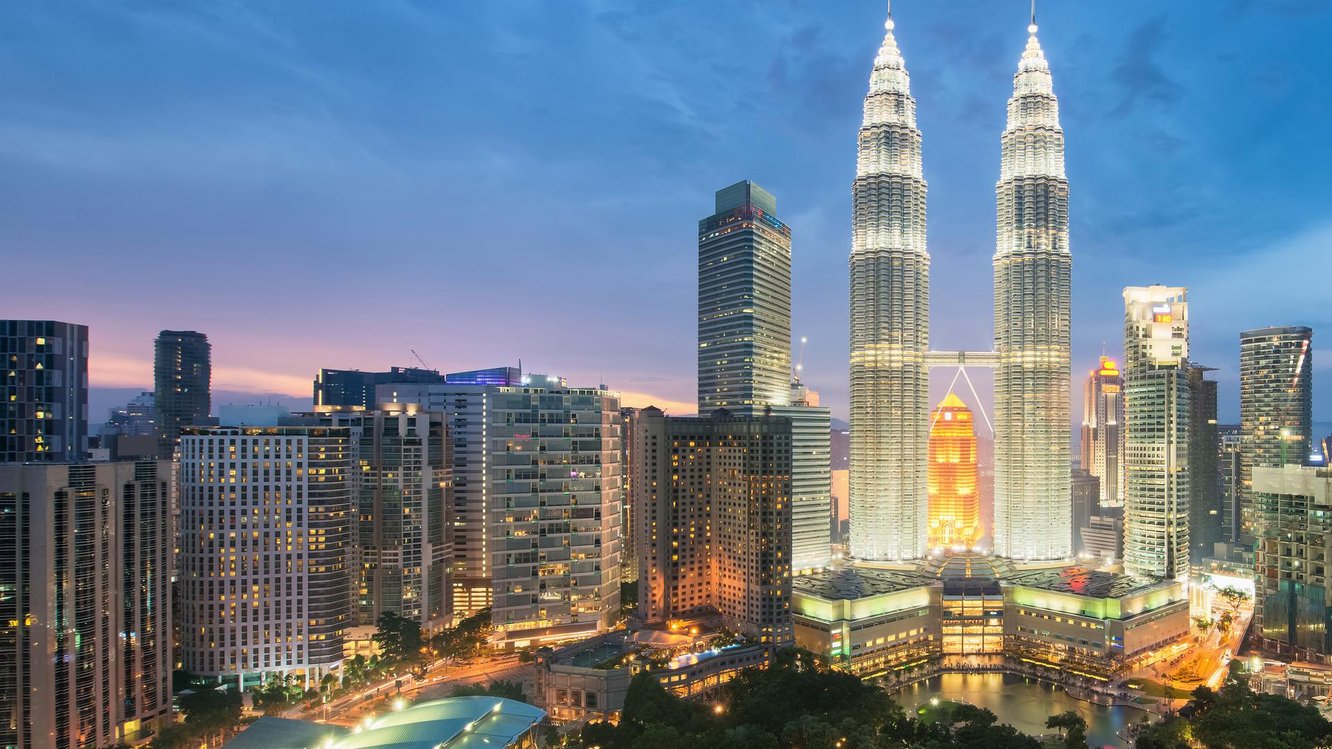 Moderne Skyline von Kuala Lumpur mit angestrahltem Doppel-Hochhaus in der Mitte