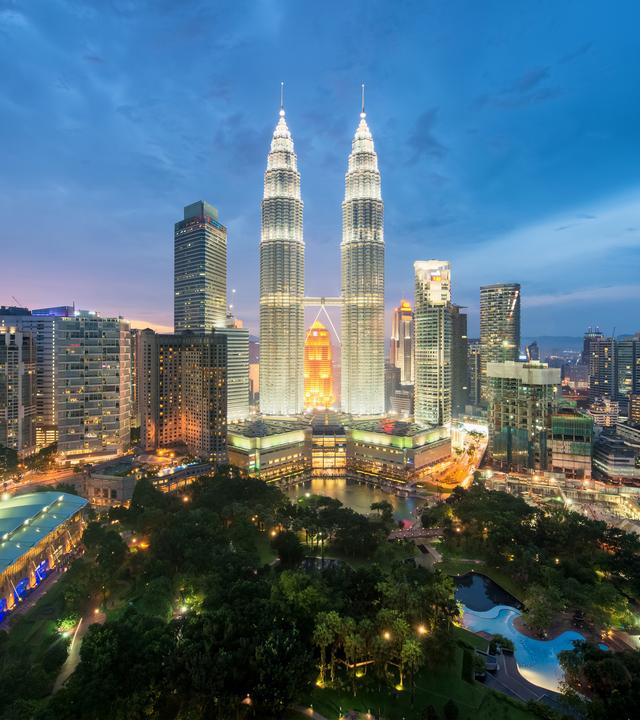 Moderne Skyline von Kuala Lumpur mit angestrahltem Doppel-Hochhaus in der Mitte