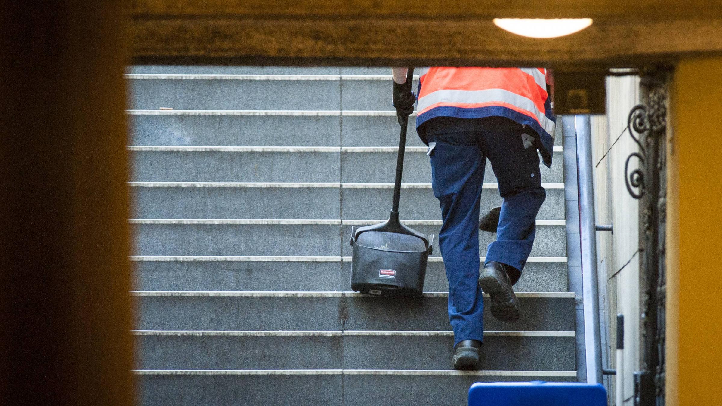 Ein Mann reinigt die Treppen zu einer U Bahn Station in Berlin