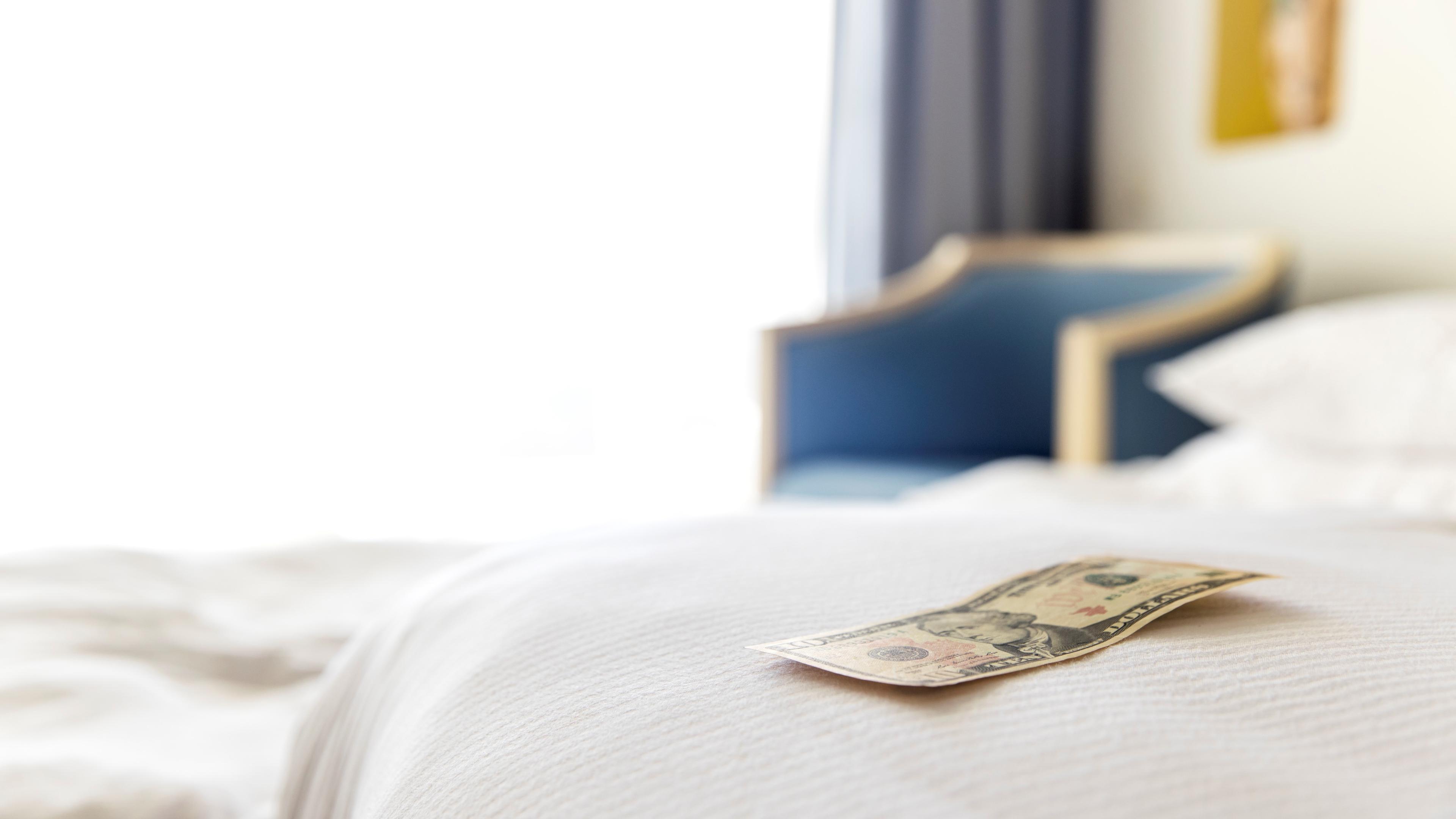 Ein Geldschein liegt auf einem Hotelbett.