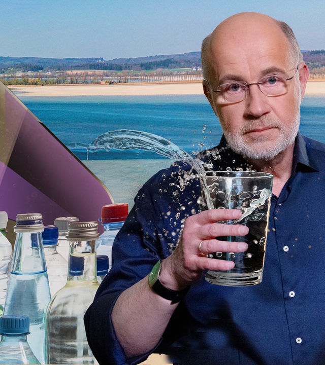 Harald Lesch hält Glas Wasser vor Bodensee mit Niedrigwasser