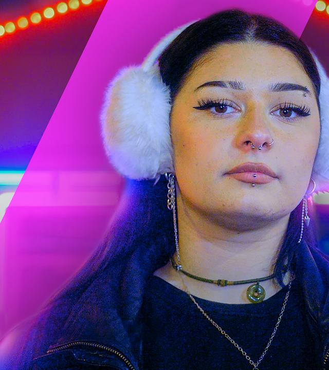 Eine junge Frau blickt in die Kamera. Sie trägt weiße Kopfhörer und Schmuck. 