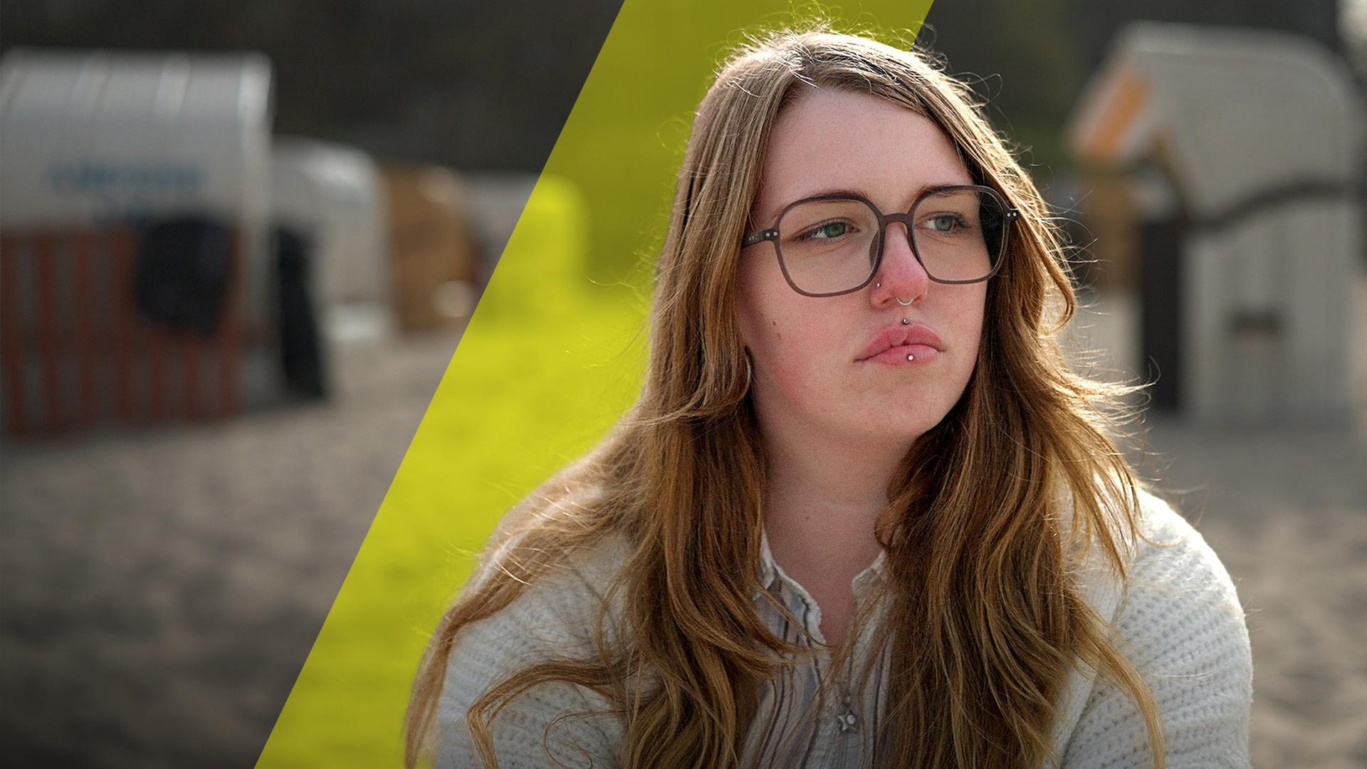Zoe schaut traurig zur Seite. Sie trägt eine Brille mit schwarzem Rand 