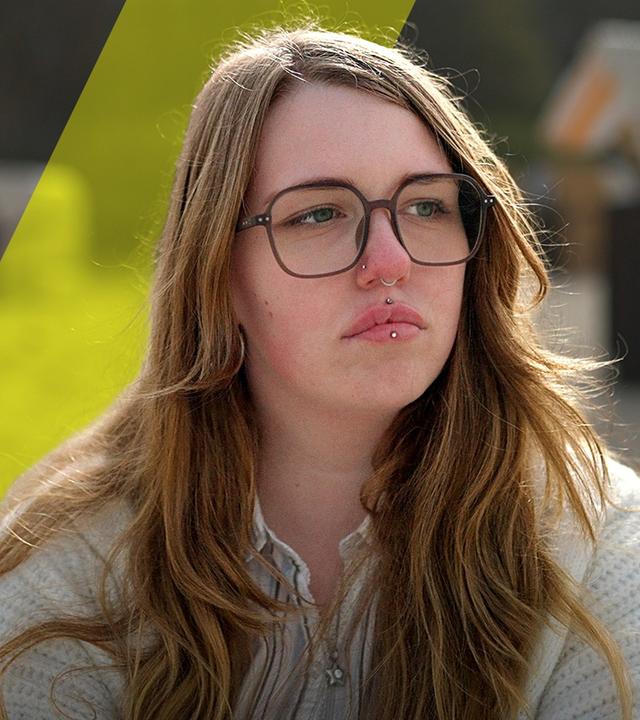 Zoe schaut traurig zur Seite. Sie trägt eine Brille mit schwarzem Rand 
