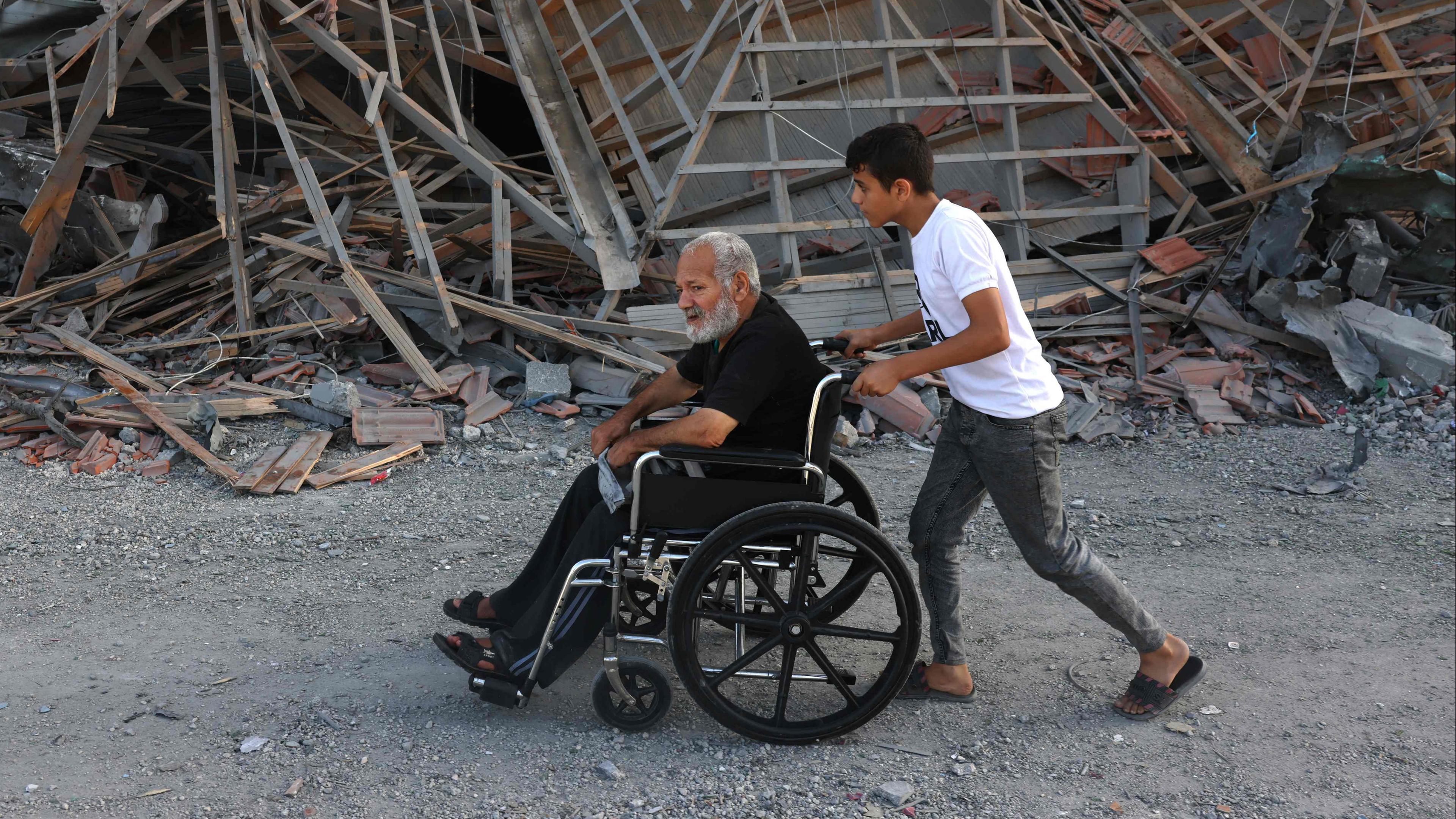 Ein palästinensischer Junge zieht einen Mann im Rollstuhl an Trümmern in Rafah im südlichen Gazastreifen vorbei