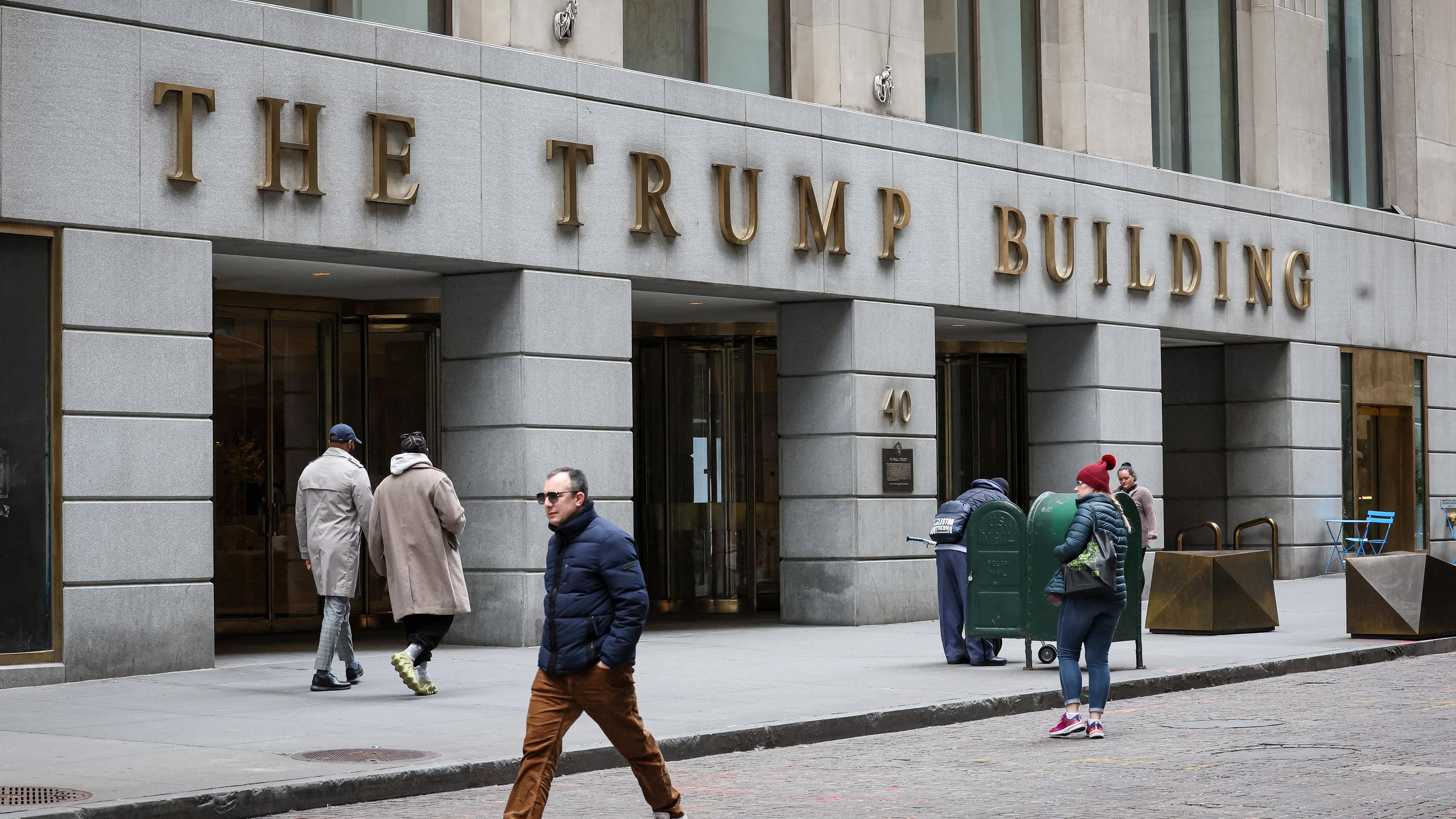 Menschen gehen vor dem Trump Building 40 Wall Street im Finanzdistrikt in New York City spazieren