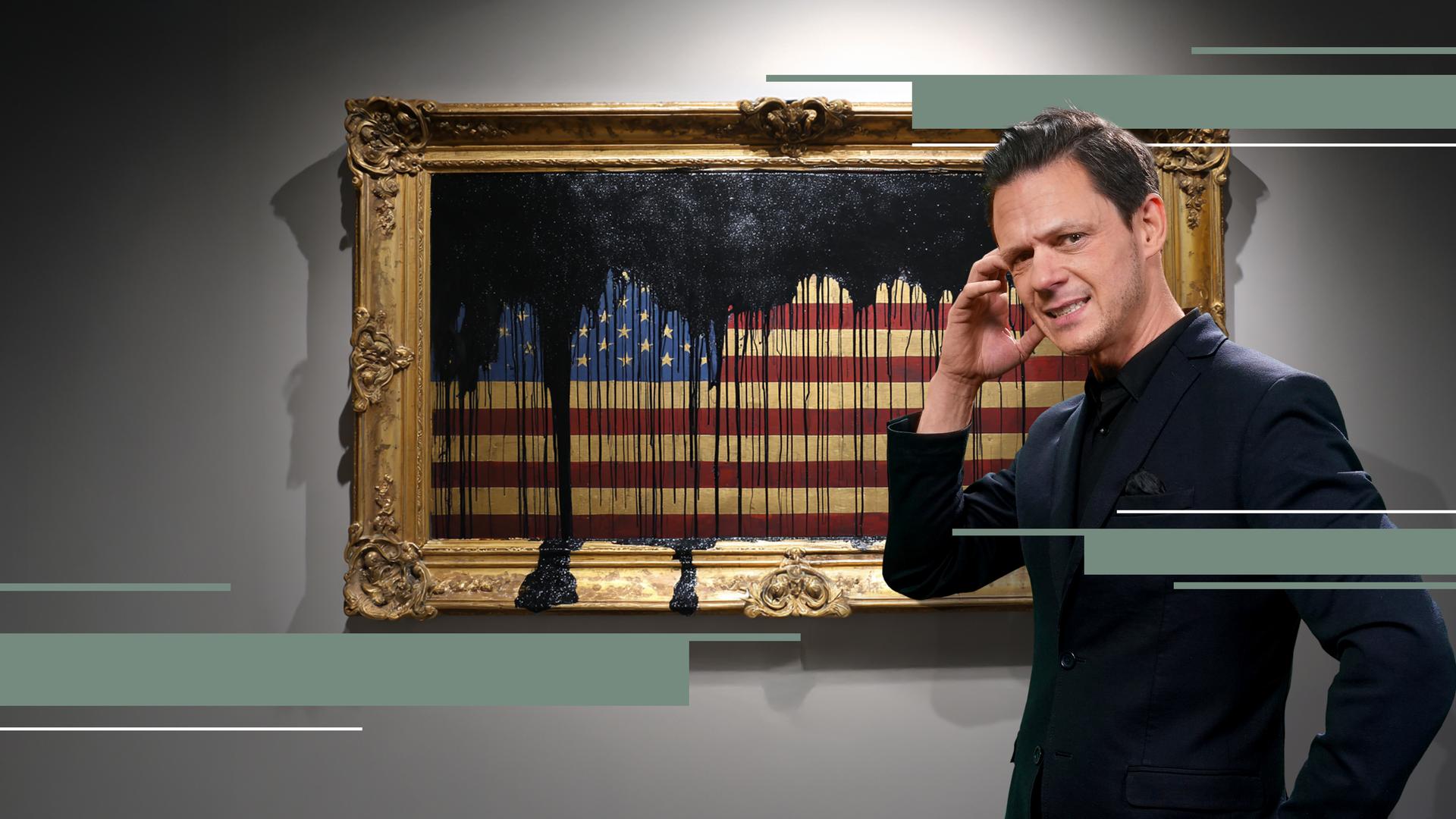 Jo Schück mit kritischem Blick vor amerikanischer Flagge in Bilderrahmen