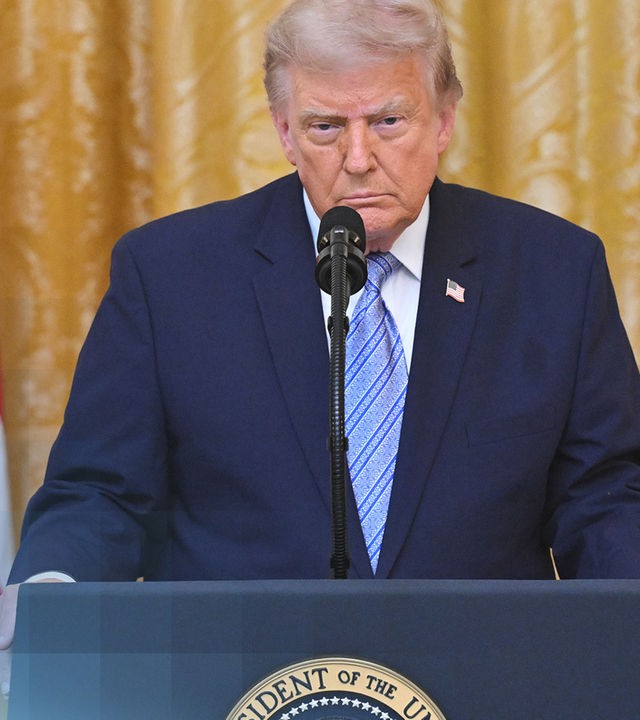 US-Präsident Donald Trump an seinem Rednerpult. Er guckt ernst und trägt einen dunkelblauen Anzug.