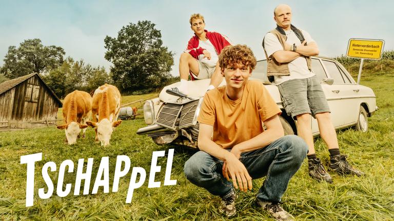 Die drei Hauptdarsteller von Tschappel auf einem Viehacker, vor einem verbeulten Mercedes /8