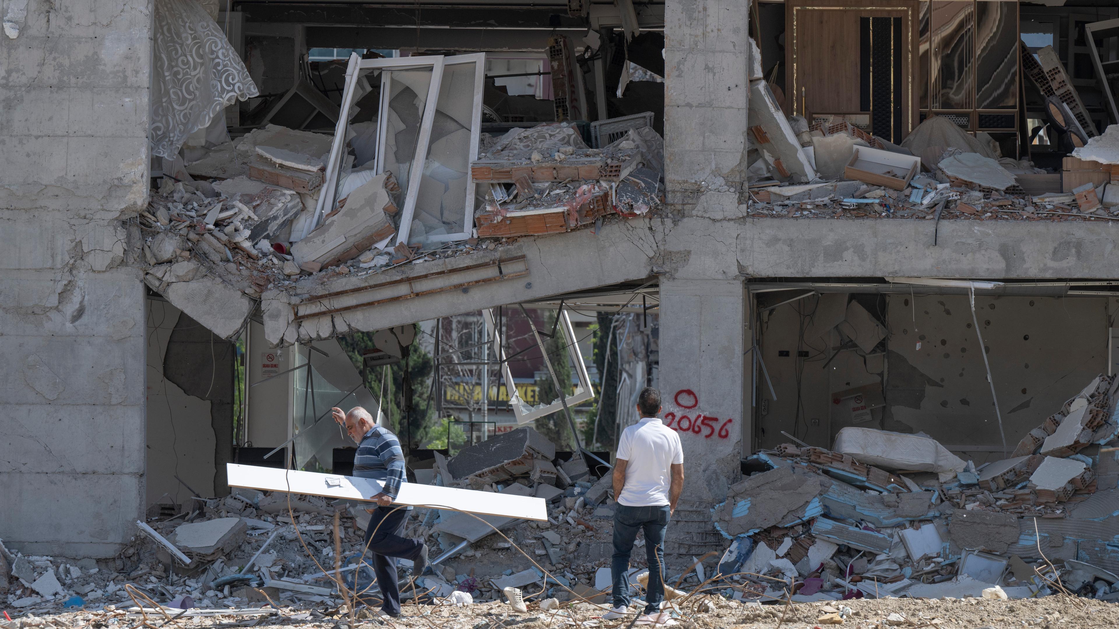 Türkei, Antakya: Anwohner gehen an einer zerstörten Häuserzeile entlang. Weite Teile der Stadt wurden bei dem Erdbeben vom sechsten Februar komplett zerstört. 