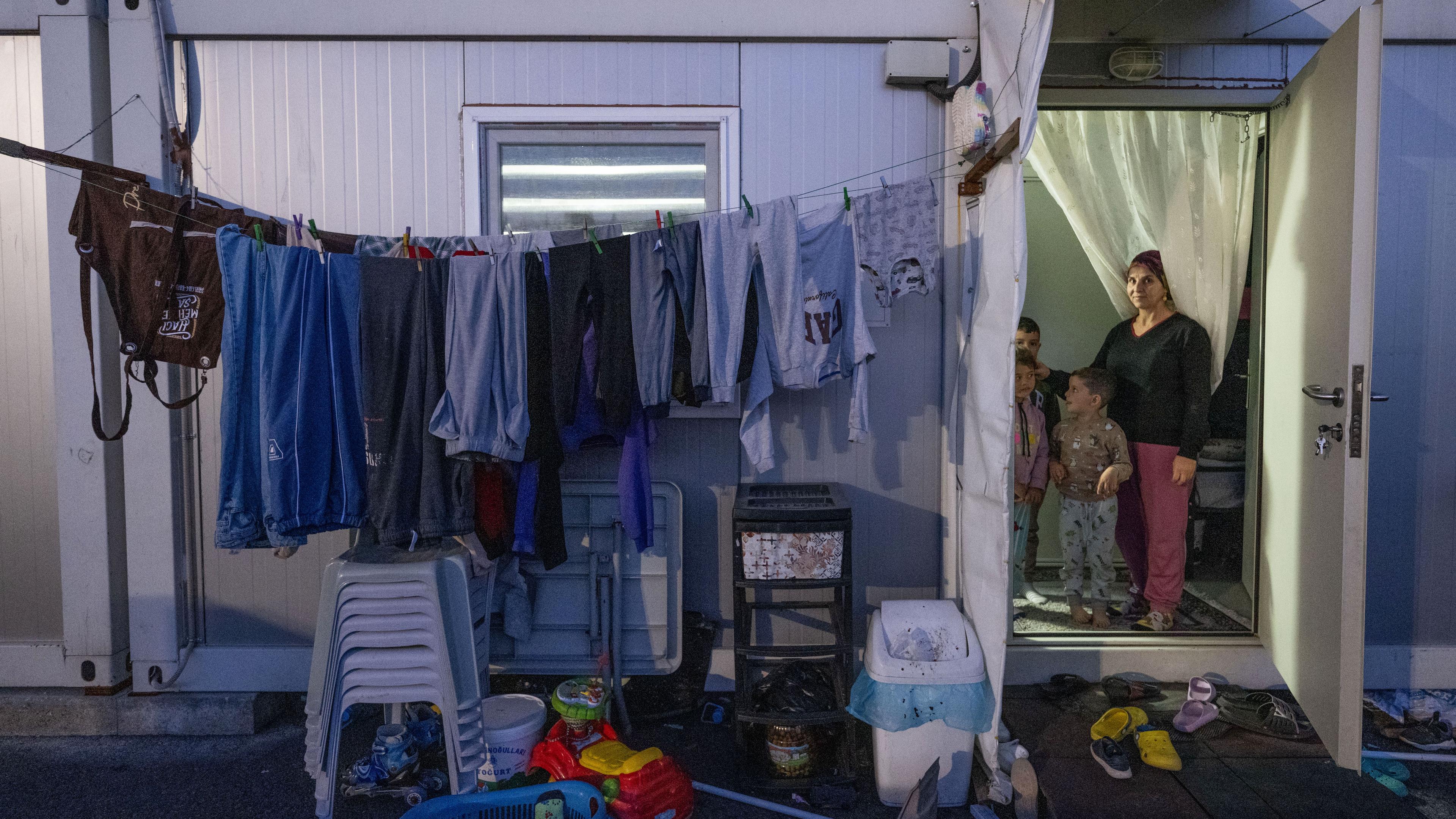 Eine Frau steht mit ihren Kindern in der Tür eines Wohncontainers bei Kahramanmaras, in dem sie mit ihrer Familie nach dem Erdbeben untergekommen ist.