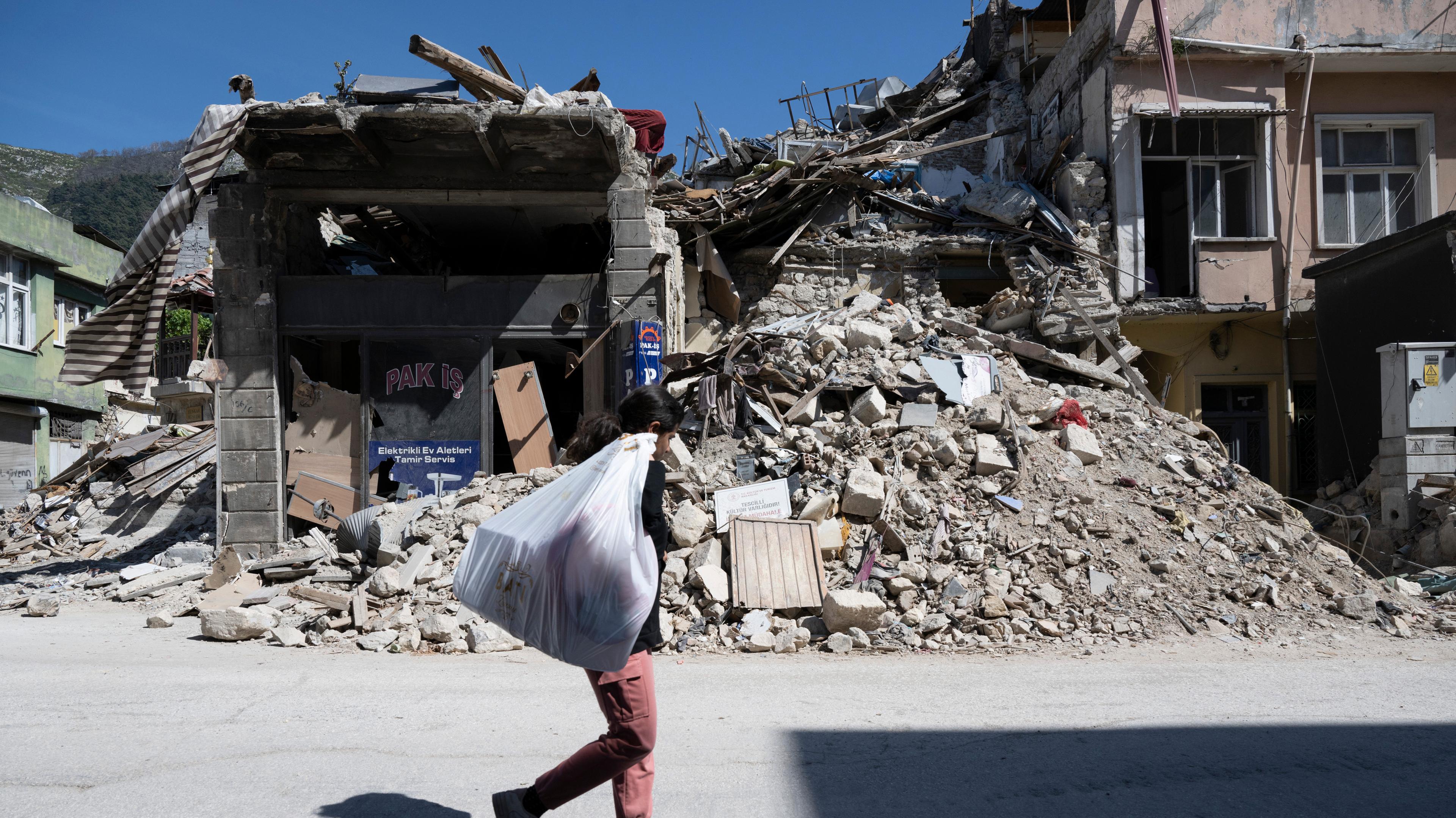 Archiv: Ein Mädchen schleppt einen Sack in den Trümmern der Altstadt von Antakya. 
