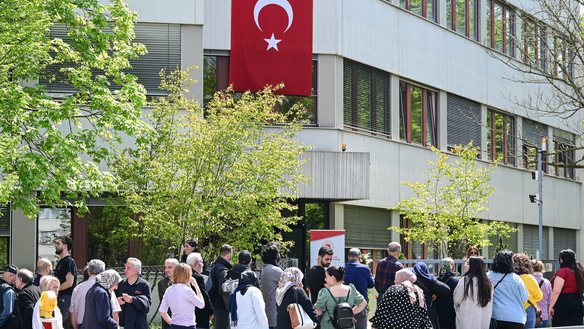 Eine Schlange an Menschen, im Hintergrund eine türkische Flagge