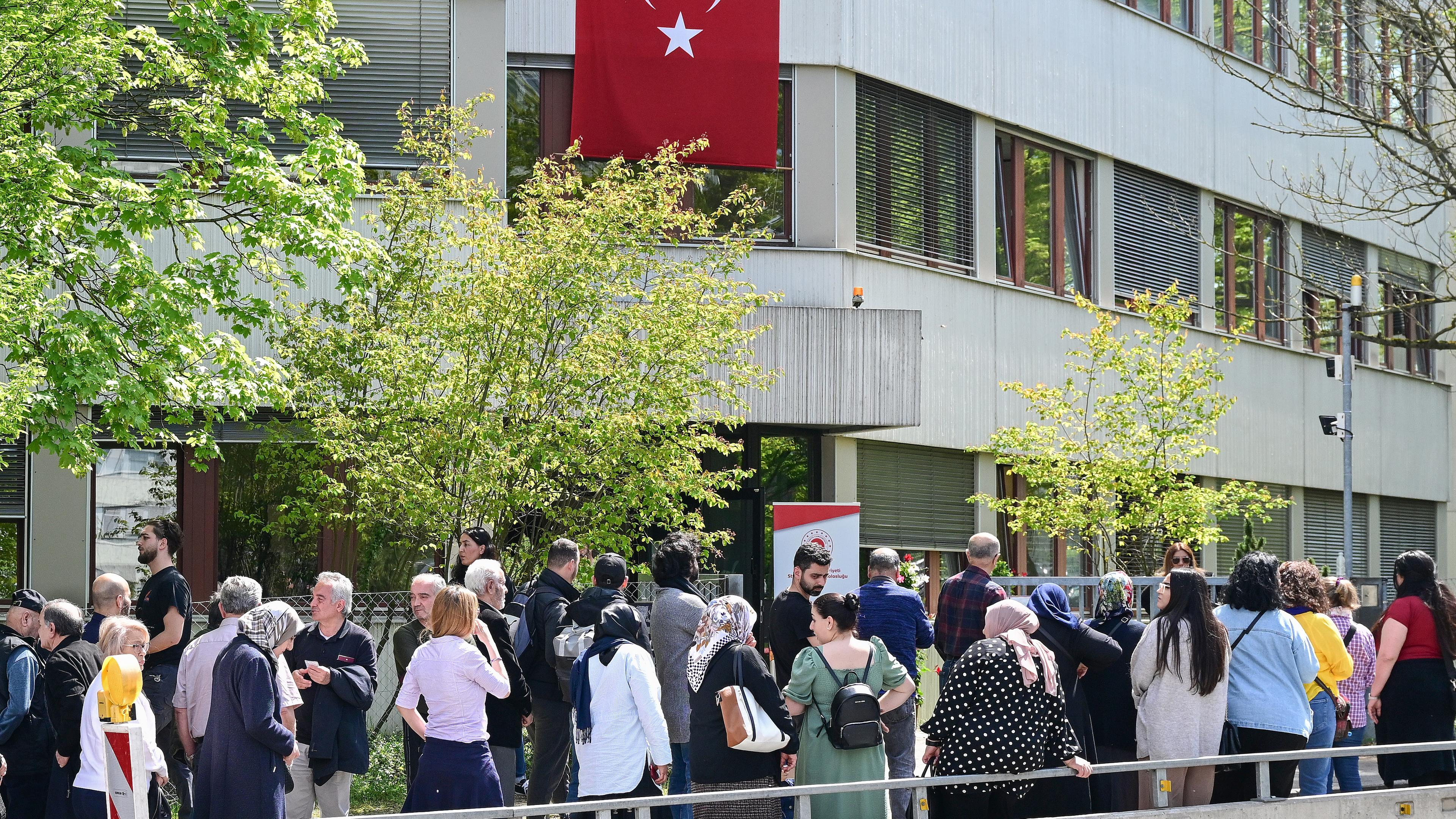 Eine Schlange an Menschen, im Hintergrund eine türkische Flagge
