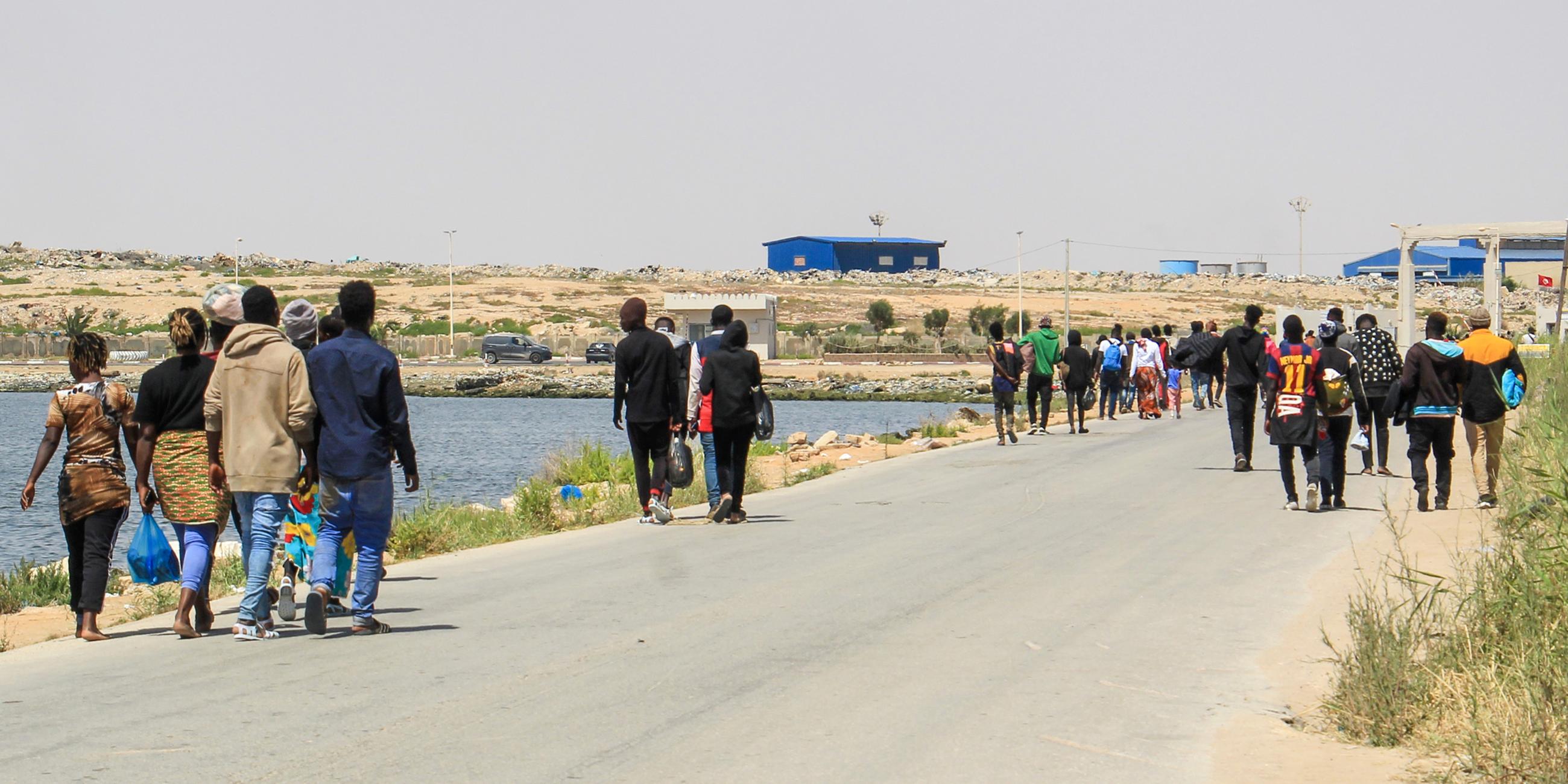 Migranten, die von tunesischen Einsatzkräften auf dem Meer aufgespürt wurden, gehen eine Straße hinunter nachdem sie am Hafen zurück an Land gelassen wurden.