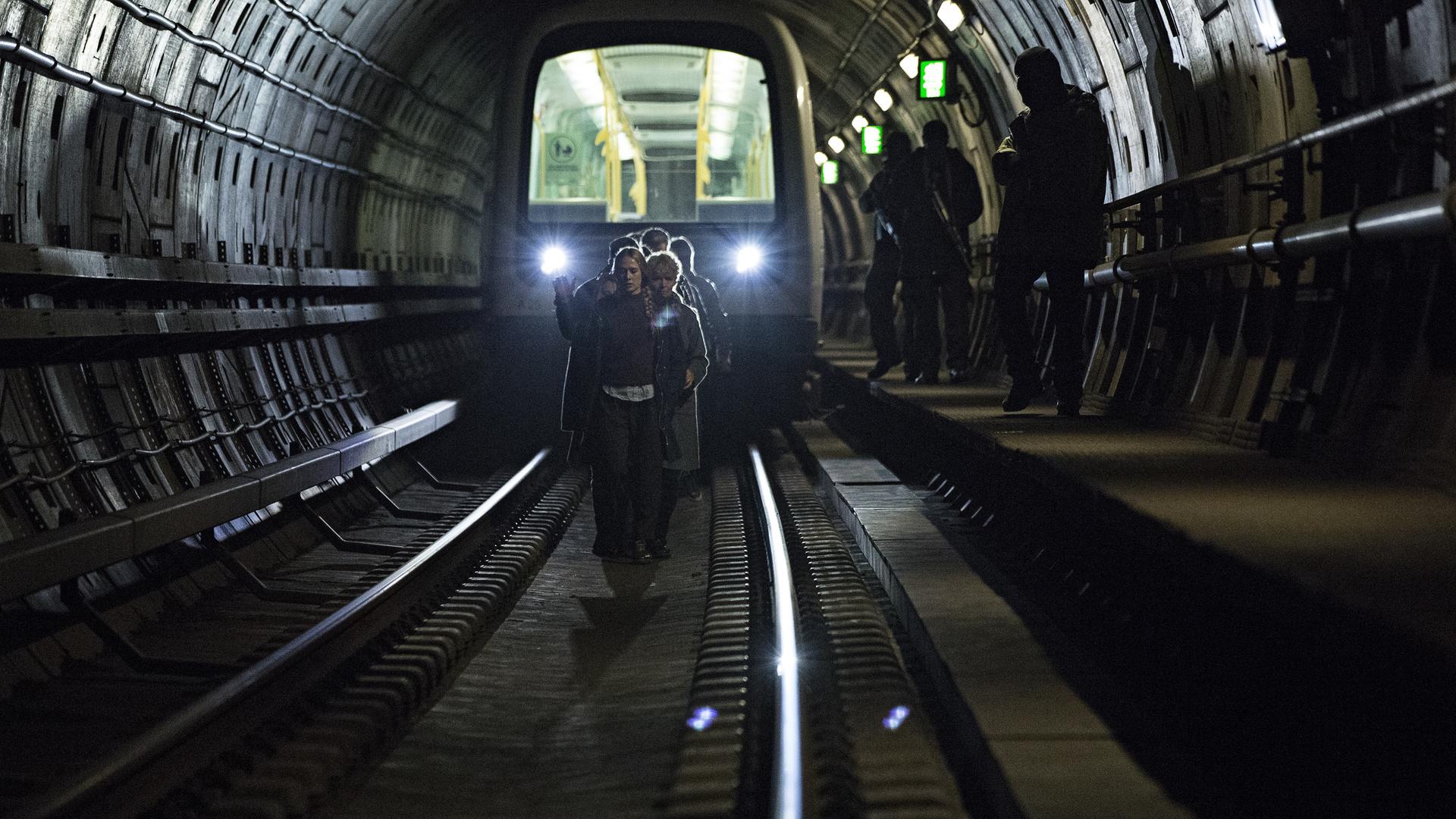 "Countdown Copenhagen - Tag 1": Bewaffnete Männer bewachen eine Gruppe von Menschen, die zu Fuß in einem U-Bahn-Tunnel laufen.