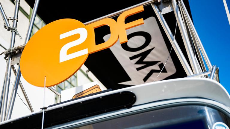 ZDF-Logo neben dem OMR-Logo aus der Froschperspektive an einer Busfront entlang fotografiert.