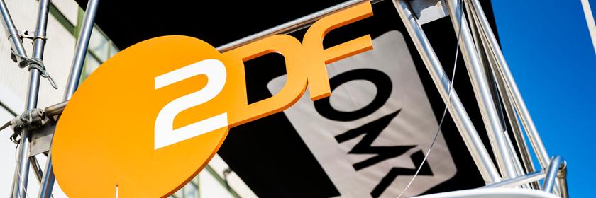 ZDF-Logo neben dem OMR-Logo aus der Froschperspektive an einer Busfront entlang fotografiert.