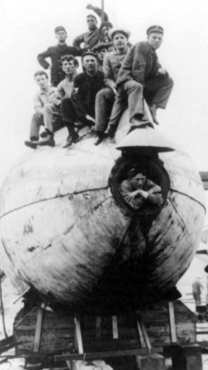 "U-Boote: Aufbruch in die Tiefe": Schwarz-Weiß-Aufnahme mit zwei großen U-Boot-Entwürfen, auf denen mehrere Menschen sitzen und für das Foto posieren.