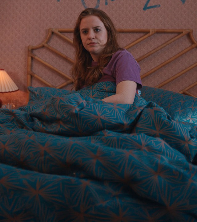 "Extraordinary - Überraschung": Jen (Máiréad Tyers) liegt in ihrem Bett und mustert ihr Schlafzimmer mit skeptischem Blick. Auf der Tapete hinter ihr steht in blauer Farbe an die Wand geschrieben "jen loves jizz".