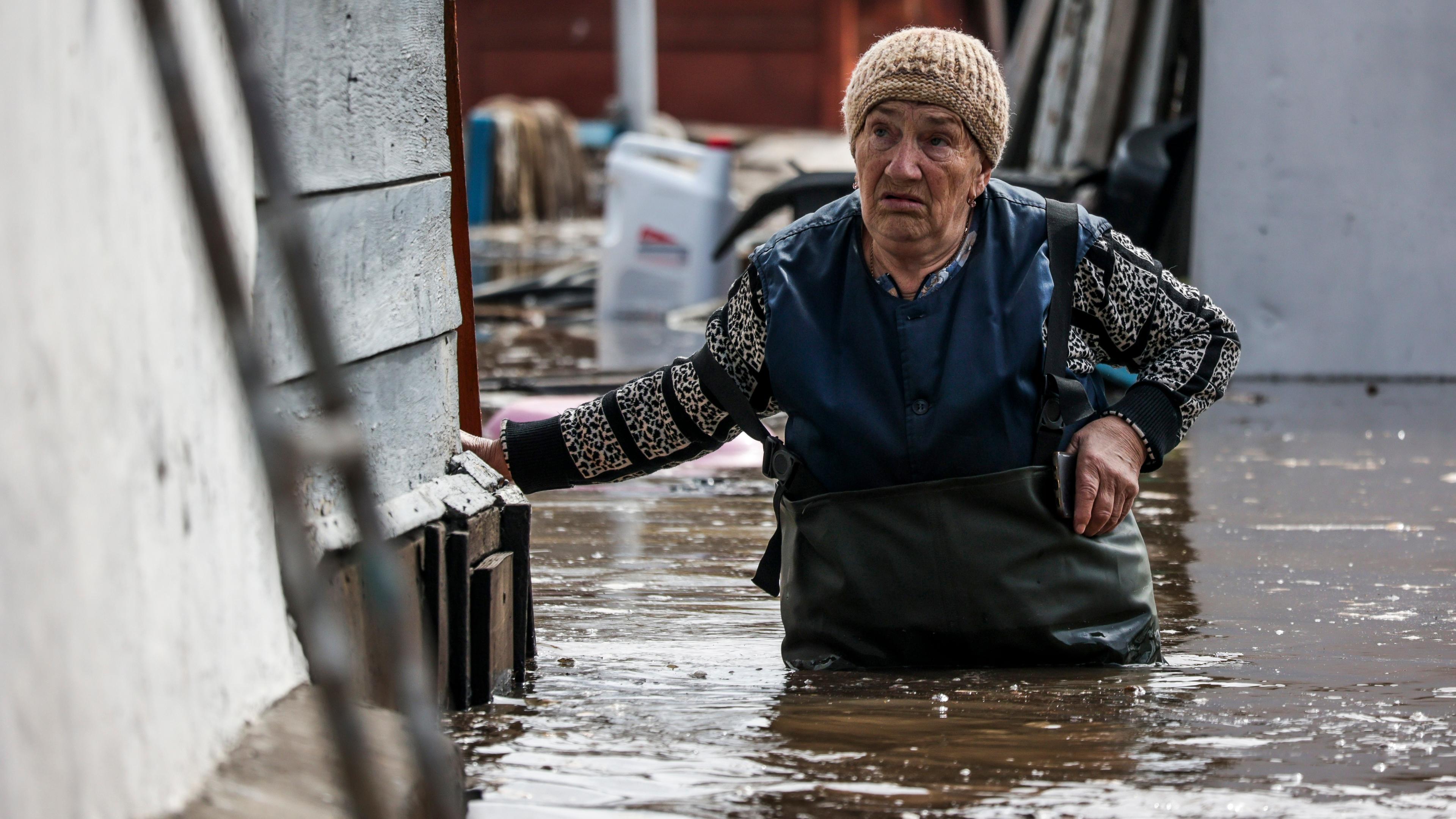 Russland, Orenburg: Eine Frau geht in der Nähe ihres Hauses in einem überschwemmten Gebiet in Orenburg, Russland. 